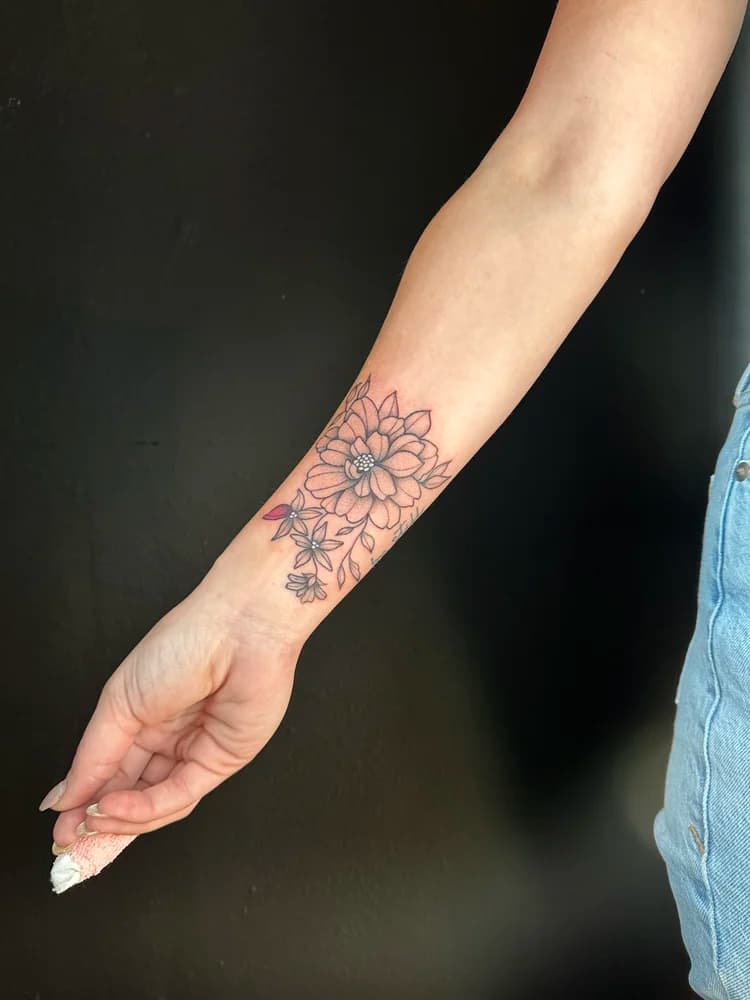 Black and pink floral forearm tattoo with sunflower and small leaves scattered