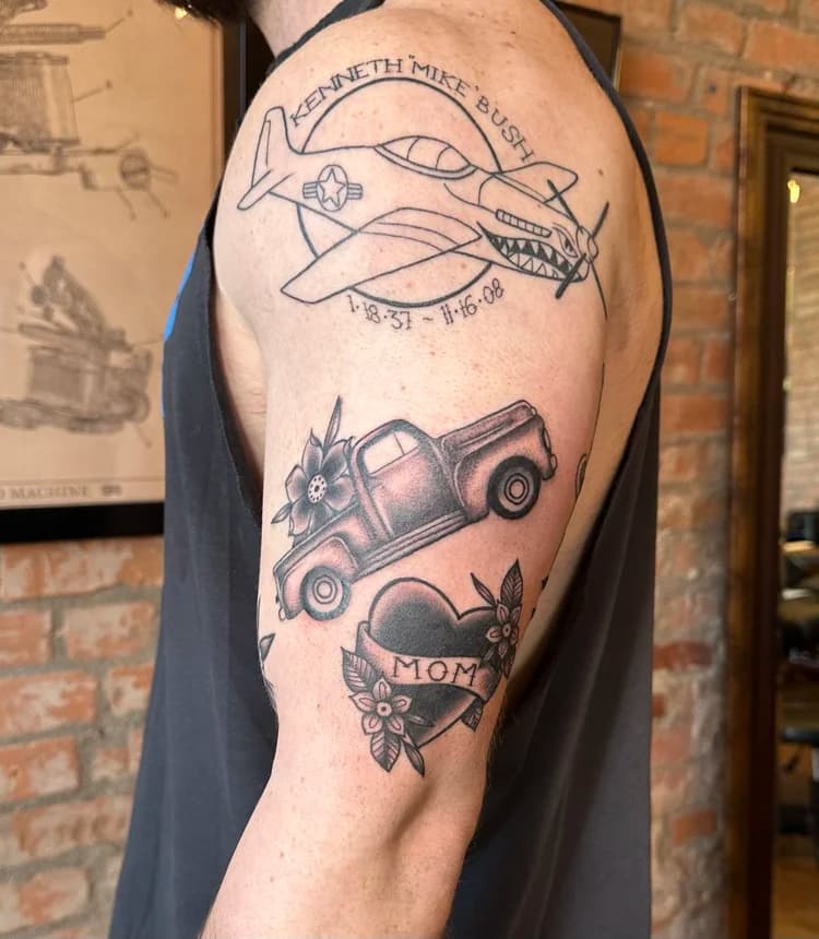 Black and gray memorial airplane tattoo on shoulder with floral elements