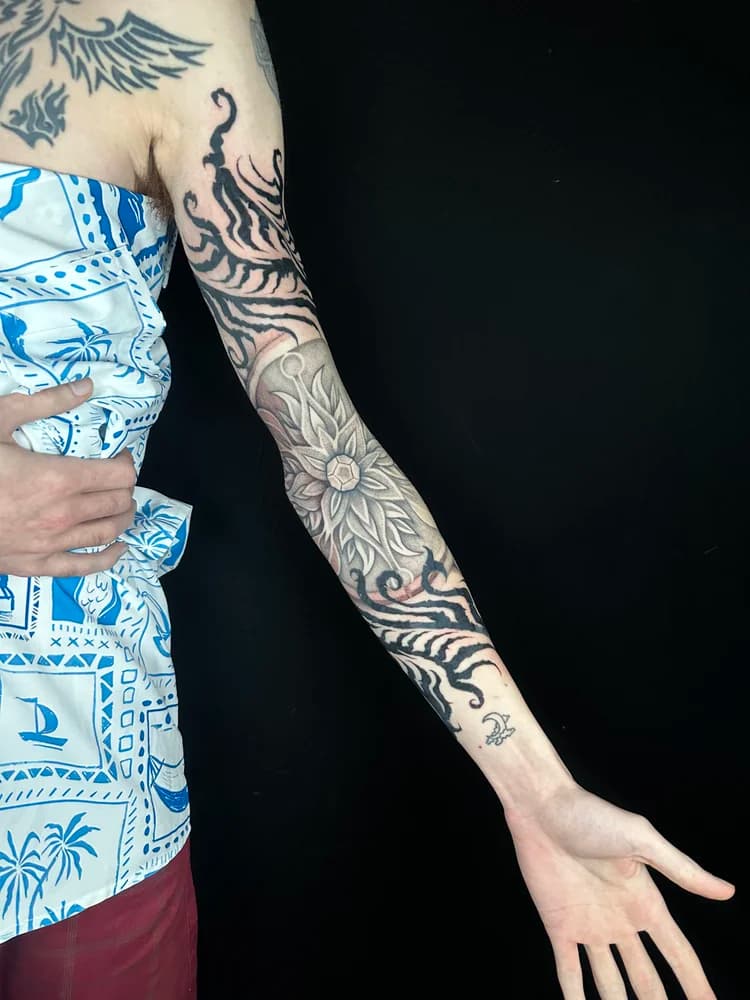 Black floral and ornamental arm sleeve tattoo on forearm with geometric designs