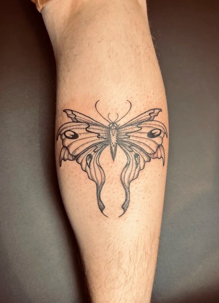 Black and gray decorative butterfly tattoo on leg with ornate line details