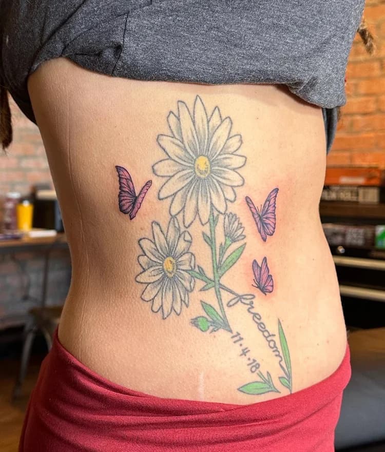 Black ink daisies and butterflies tattoo on ribcage with colored yellow center