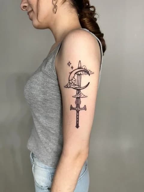 Black line art moon and cross tattoo on arm with celestial design elements