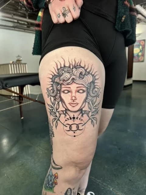 Black and gray medusa head portrait tattoo on thigh with detailed line shading